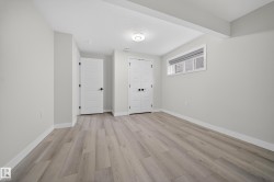 Spacious room featuring wood-finish flooring, light grey walls, and white trim - 