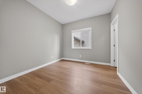 Room featuring wood-finish flooring, light gray walls, white baseboards, and a window with horizontal blinds - 3639 15A Street Nw, Edmonton, AB - Indoor Photo Showing Other Room