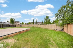 Spacious backyard featuring a large paver patio, a perimeter wood fence, and mature trees - 