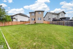 Spacious backyard featuring a large grass area, a partial wood fence, and a two-story exterior with multiple windows - 