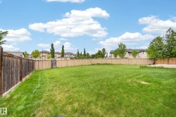 Expansive grass lawn bordered by a wood fence, featuring a partial concrete pad - 