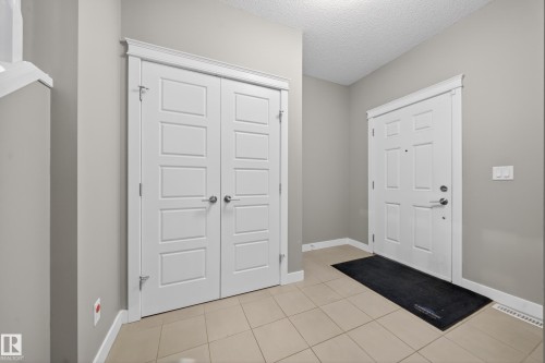 Entryway featuring tile flooring, a paneled front door, and a double-door closet with white trim - 3639 15A Street Nw, Edmonton, AB - Indoor Photo Showing Other Room