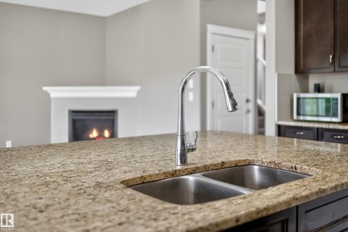 Kitchen island with a double basin stainless steel sink, gooseneck faucet, and mottled countertop - 3639 15A Street Nw, Edmonton, AB - Indoor Photo Showing Kitchen With Double Sink