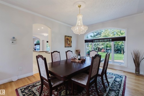 Hardwood flooring throughout this dining space with an arched window overlooking the backyard - 928 Heacock Road Nw, Edmonton, AB - Indoor Photo Showing Dining Room