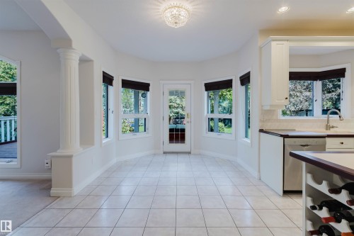 Bright dining area featuring tile flooring, multiple windows, a glass-paned exterior door, and an ornate ceiling light fixture - 928 Heacock Road Nw, Edmonton, AB - Indoor
