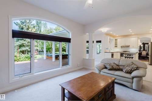 Arched window overlooking a wooden deck with an outdoor spa - 928 Heacock Road Nw, Edmonton, AB - Indoor Photo Showing Living Room