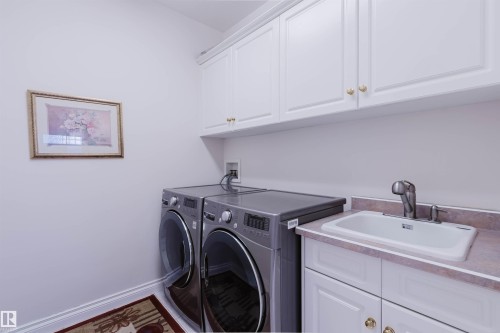 Laundry area featuring white cabinetry with gold-toned hardware, a utility sink with a chrome faucet, and ample countertop space - 928 Heacock Road Nw, Edmonton, AB - Indoor Photo Showing Laundry Room