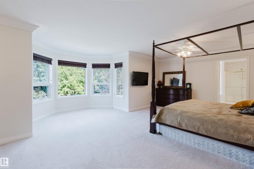 Spacious carpeted room featuring a rounded wall with multiple windows, crown molding, and a built-in ceiling fan - 928 Heacock Road Nw, Edmonton, AB - Indoor Photo Showing Bedroom