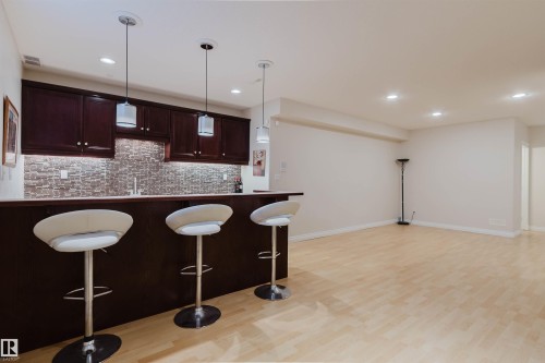 Entertainment space featuring a wet bar with dark wood cabinetry, a mosaic tile backsplash, and a light-toned countertop - 928 Heacock Road Nw, Edmonton, AB - Indoor Photo Showing Kitchen