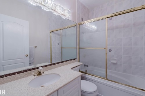 Bathroom vanity featuring a light-colored countertop, integrated sink, and an extensive mirror - 928 Heacock Road Nw, Edmonton, AB - Indoor Photo Showing Bathroom