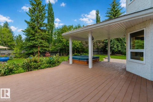 Spacious outdoor entertaining area featuring a wood-finish deck, covered patio, and integrated hot tub - 928 Heacock Road Nw, Edmonton, AB - Outdoor With Deck Patio Veranda