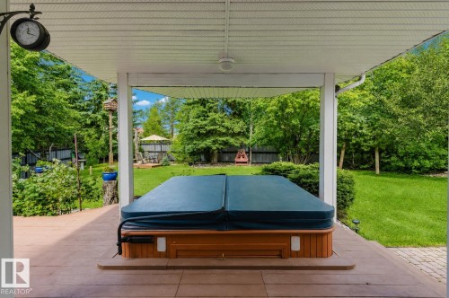 Covered outdoor patio featuring a hot tub with wood-finish siding, composite decking, and a ceiling fan - 928 Heacock Road Nw, Edmonton, AB - Outdoor With Deck Patio Veranda With Exterior