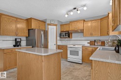 Kitchen featuring wood cabinetry, light-toned countertops, a central island, and vinyl plank flooring - 
