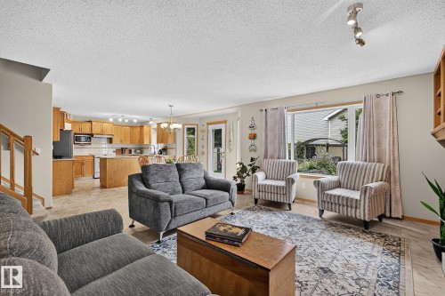Open-concept living space featuring wood-finish flooring, a kitchen with light wood cabinetry and a central island, and a dining area with a chandelier - 385 Meadowview Terrace, Sherwood Park, AB - Indoor Photo Showing Living Room