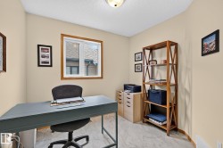 Versatile room used as a den featuring light-toned wall paint, a window with wood trim, and light-toned flooring - 