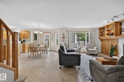Open-concept living space featuring wood-finish flooring throughout, a kitchen with light wood cabinetry, and a eating area with a glass-paned door leading to the back yard - 