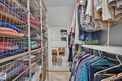 Walk-in closet in the primary bedroom featuring extensive wire shelving storage, a multi-tiered shoe rack, and integrated clothing rods - 