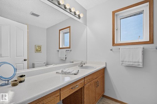 Bathroom vanity in the ensuite featuring a long countertop with an integrated sink, light wood-finish cabinetry, and a full-width mirror - 385 Meadowview Terrace, Sherwood Park, AB - Indoor Photo Showing Bathroom