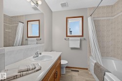 Main upstairs bathroom vanity with integrated sink, chrome faucet, and wood-finish cabinetry - 
