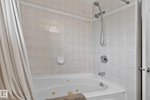 Main upstairs bath includes a tub with integrated jets and chrome fixtures, surrounded by light-toned wall tiling - 385 Meadowview Terrace, Sherwood Park, AB - Indoor Photo Showing Bathroom
