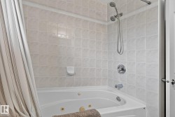 Main upstairs bath includes a tub with integrated jets and chrome fixtures, surrounded by light-toned wall tiling - 