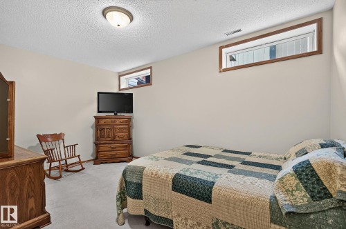 Bedroom 4 in the basement is a large carpeted room featuring a ceiling-mounted light fixture, two transom windows with wood trim, and neutral wall tones - 385 Meadowview Terrace, Sherwood Park, AB - Indoor Photo Showing Bedroom