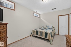 Bedroom 4 is a carpeted basement room featuring light-toned walls, a textured ceiling, and two upper-level windows with wood trim - 