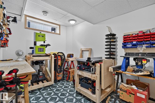 Bedroom #5 is currently used as a workshop serving as a versatile utility space featuring a drop ceiling with integrated lighting, white painted walls, and patterned flooring - 385 Meadowview Terrace, Sherwood Park, AB - Indoor