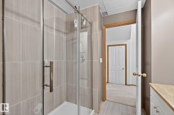 Basement bathroom has a shower enclosure with clear glass doors and brushed nickel hardware - 