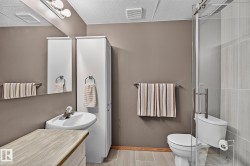 Contemporary 3-pc bathroom in the basement featuring a corner-mounted sink, a glass-enclosed shower, and a built-in storage cabinet - 