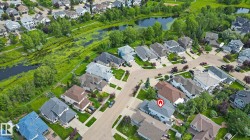 Aerial perspective showcasing a residential area and earby park with varied home designs, a curving street pattern, and numerous mature trees - 