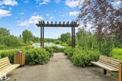 Landscaped path with a dark wood pergola, flanked by lush green bushes and mature trees - 