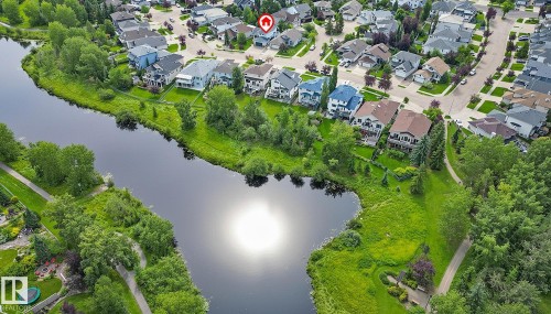 Aerial perspective showcasing the neighborhood with homes featuring diverse architectural styles and rooflines near Clarkdale Meadows Pond - 385 Meadowview Terrace, Sherwood Park, AB - Outdoor With Body Of Water With View