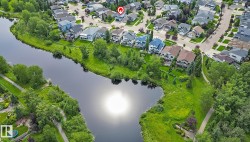 Aerial perspective showcasing the neighborhood with homes featuring diverse architectural styles and rooflines near Clarkdale Meadows Pond - 