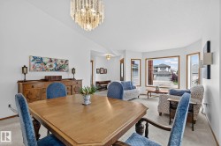 Spacious dining area featuring a tiered crystal chandelier, wood-finish flooring, and a large bay window - 