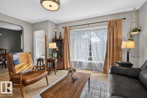 Living area featuring a bay window, wood-finish flooring, and a decorative ceiling light fixture - 11934 43 Street Nw, Edmonton, AB - Indoor Photo Showing Living Room