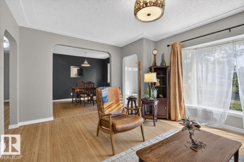Living area featuring wood-finish flooring, light gray walls, and a decorative ceiling light fixture - 11934 43 Street Nw, Edmonton, AB - Indoor