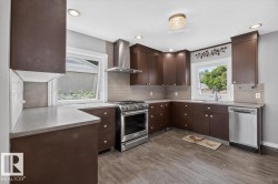 Kitchen featuring dark wood-finish cabinetry, stainless steel appliances, light countertops, and wood-look tile flooring - 