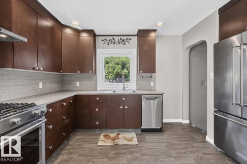 Kitchen featuring rich wood-finish cabinetry, stainless steel appliances, light-toned countertops, and a subway tile backsplash - 11934 43 Street Nw, Edmonton, AB - Indoor Photo Showing Kitchen