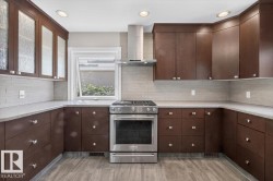 Modern kitchen featuring wood-finish cabinetry, light-toned countertops, and a full stainless steel range with a coordinating hood vent - 