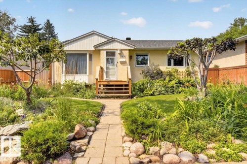 Inviting stucco residence featuring a landscaped front yard with a stone paver pathway, mature trees, and established plantings - 11934 43 Street Nw, Edmonton, AB - Outdoor