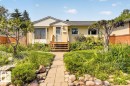 Inviting stucco residence featuring a landscaped front yard with a stone paver pathway, mature trees, and established plantings - 11934 43 Street Nw, Edmonton, AB  - Outdoor 