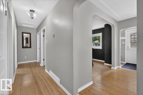 Hardwood-style flooring throughout a neutral-toned hallway with white trim - 11934 43 Street Nw, Edmonton, AB - Indoor Photo Showing Other Room