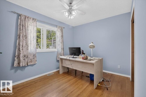 Bedroom featuring wood-finish flooring, a white window frame, and a ceiling fan with integrated lighting - 11934 43 Street Nw, Edmonton, AB - Indoor Photo Showing Office