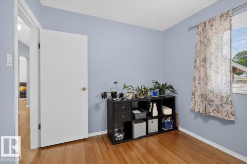 Room featuring wood-finish flooring, light blue wall paint, a white trim, and a window with white casing - 11934 43 Street Nw, Edmonton, AB - Indoor Photo Showing Other Room