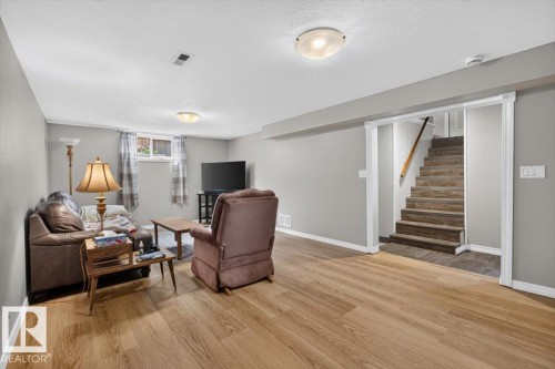 Spacious living area featuring wood-finish flooring, light gray walls, and recessed windows - 11934 43 Street Nw, Edmonton, AB - Indoor