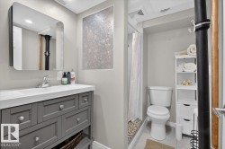 Contemporary bathroom featuring a vanity with gray cabinetry and a white countertop - 
