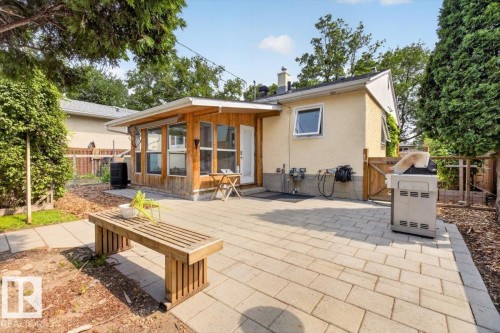 Expansive backyard patio featuring paver stones, a sunroom with wood siding, and mature perimeter landscaping - 11934 43 Street Nw, Edmonton, AB - Outdoor With Deck Patio Veranda With Exterior