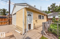 Detached garage with a single overhead door, stucco exterior, side entry door, and multiple windows - 