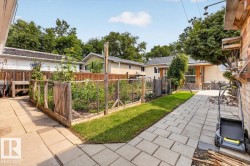 Expansive backyard featuring a fenced garden bed, paver patio, and well-maintained lawn - 